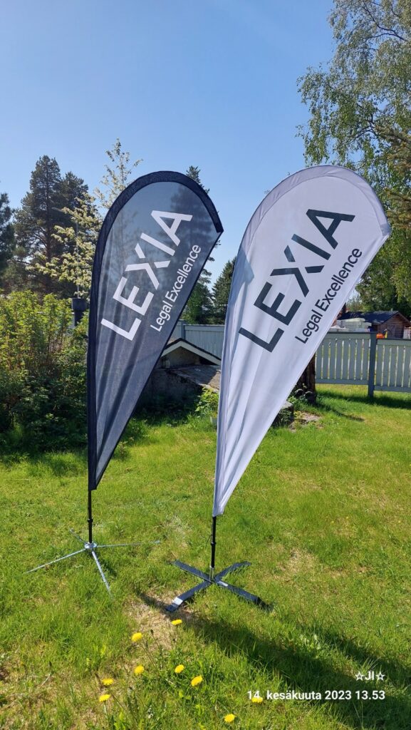 Kaksi Lexia Legal Excellence -mainoslippua pystytettynä ulkona nurmikolla